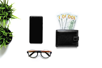 Flatlay of money in black wallet, mobile phone, glasses on white background.