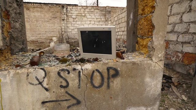 Smashed old computer monitor on ruined building wall