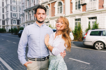 Portrait of cute couple walking around British quarter. Handsome guy looking seriously, blonde girl...