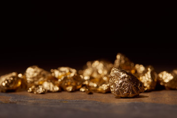 selective focus of golden stones on dark marble isolated on black