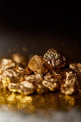 selective focus of golden stones on dark sparkling surface and black background