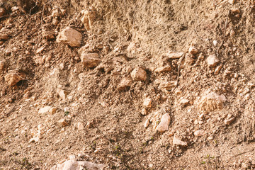 Art background of light brown soil with stones. Land textured wall for publication, poster, calendar, post, screensaver, wallpaper, postcard, postcard, banner, cover, website. High quality photography