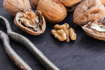 Walnuts with nutcracker, on black surface