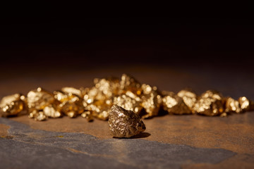 selective focus of golden stones on marble and black blurred background
