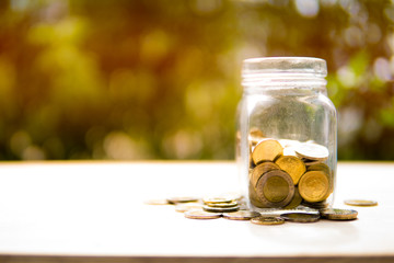 Coin and jar put on wooden table present the Savings Coins - Investment And Interest and retirement Concept.