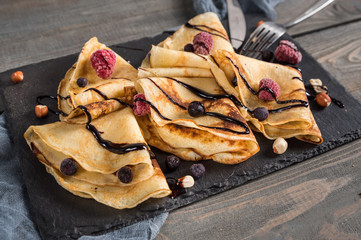 Sweet crepes wrapped with fresh berries and chocolate - obrazy, fototapety, plakaty