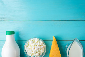 Dairy products. Cottage cheese, cheese, milk and kefir on blue wooden background with copy space.