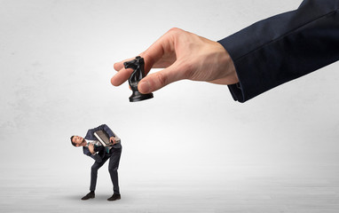 Big hand holding chessman and down little afraid businessman concept in a light space
