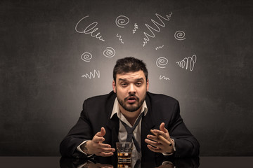 Young drunk man at his office with doodles around
