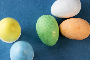 Several multi-colored decorative eggs on blue background. Easter concept.