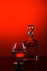 glass and carafe with alcohol on a red background