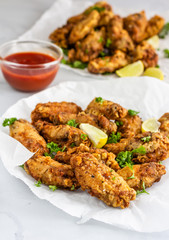 Crispy Baked Chicken Wings with Lemon Wedges and Red Chili Sauce