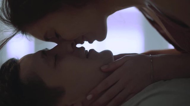 Girl rubbing noses with her boyfriend, then kissing. Loving couple rest at home together. Leisure of young family