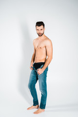 handsome bearded man in jeans posing on grey