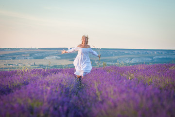 Beautiful woman in white dress runs in a lavender field
