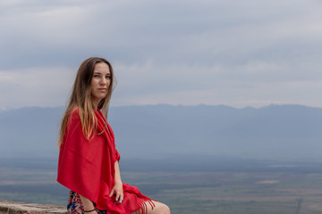 young beautiful happy girl with a red scarf on her shoulders travels around Georgia