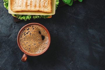 Cup with hot coffee and sandwich with grilled toast, salami sausage, salad lettuce, spinach leaves...