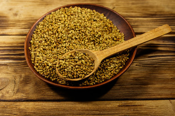 Fenugreek seeds in ceramic plate on wooden table