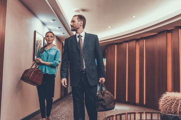 Man and woman walking with their suitcases in hotel