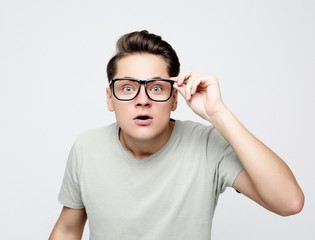 young man with emotions on his face a grey background