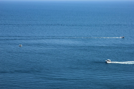 best blue sea in full screen and small ripples on the water and two motor boats cross the water surface