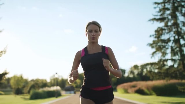 Athlete woman jogging in park. Female runner breathing hard at outdoor training
