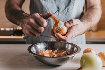 Closeup professional chef hands cleans large white onions