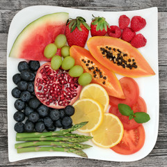 Superfood for losing weight with fresh fruit vegetables on a porcelain square plate on rustic wood background. Foods high in anthocyanins, dietary fibre, antioxidants and vitamins.