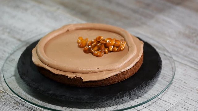 The confectioner making chocolate cake with caramel peanuts. Step by step assembly chocolate ceke.