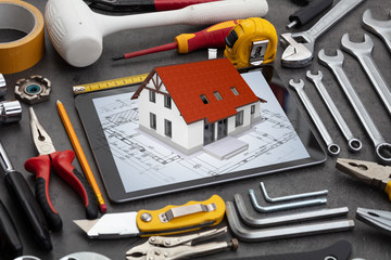 Tablet with construction tools and 3d home plan concept
