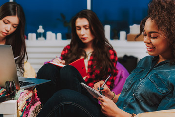 Happy multiracial women noting in memo pad