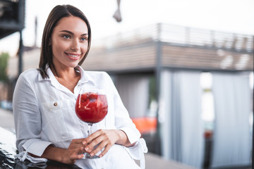 Dark haired woman standing with cocktail and smiling