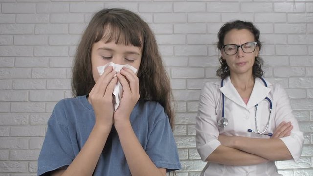 Sick child at the doctor. A sick little girl blows her nose in the doctor's office.