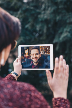 Young woman using a tablet by having a video call chat with her businessman boyfriend who is away on a business trip. Concept of keeping a long distant relationship in a career oriented world.