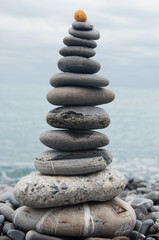 Gray stones in equilibrium on the beach in front of a stormy sea and sky of Camogli
