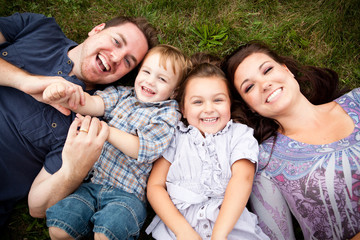 Happy Young Family Lying in Grass Together Outside