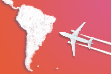 Model airplane design miniature red background fluffy clouds in the shape of continent South...
