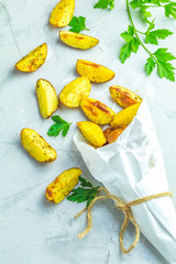 Baked potato wedges on paper with parsley