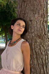 Beautiful smiling woman in ethnic style necklace in autumn park. Portrait of attractive girl.