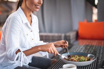 Close up of smiling woman eating salad while sitting alone