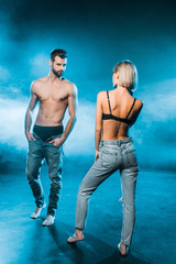beautiful couple in jeans and underwear posing on blue smoky background