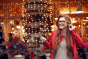 Charming red-haired girl holding cellphone and listening music