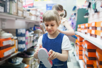 Girl   choosing summer shoes in   store.