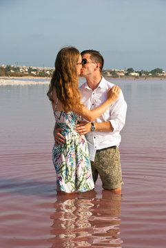 Couple of lovers in pink lake with reflection. Man and woman kiss background. Romantic picture. People in nature.