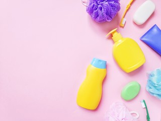 Flat lay toiletries set. Yellow shampoo bottle, liquid soap, cream, purple sponge, toothbrushes. Top view photo bath products, cosmetics for skin, oral, hair care. Bathroom stuff