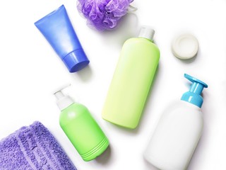 Flat lay photo toiletries set. Green shampoo bottle, liquid soap, shower gel, cream, purple towel...