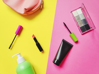 Flat lay photo content female cosmetic bag. Mascara brush, red lipstick, face cream, eyeshadow. Top view composition