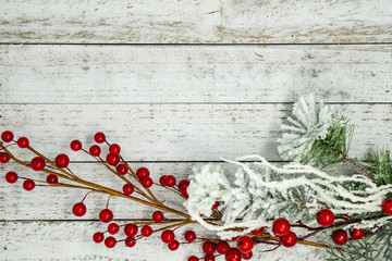 White flocked branches, twigs and berries, isolated on white wood background. Useful for Christmas and winter holiday backgrounds, messages and banners