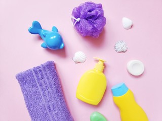 Obraz na płótnie Canvas Flat lay photography baby bath products for skin and hair care. Beauty still life photo. Purple cotton towel, toy dolphin, yellow liquid soap packaging, shampoo and seashells