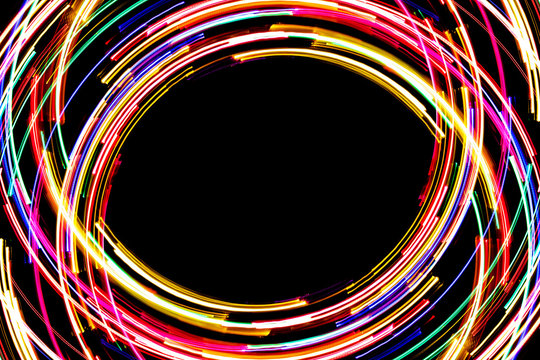 Abstract rotating neon lights texture with black empty copy space inside.